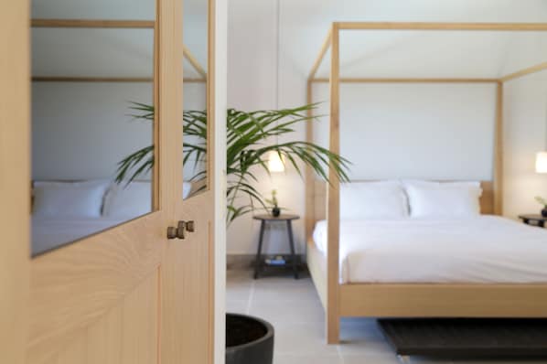 A bedroom with a wooden four-poster bed, a small bedside table, a lamp, and a potted plant. - Lena Mare Boutique Hotel (Corfu)