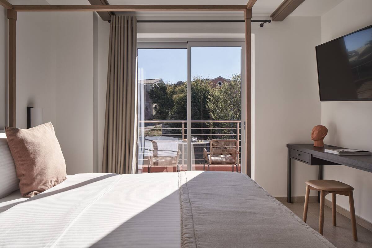 Une chambre avec un grand lit, un bureau, une chaise et un téléviseur.