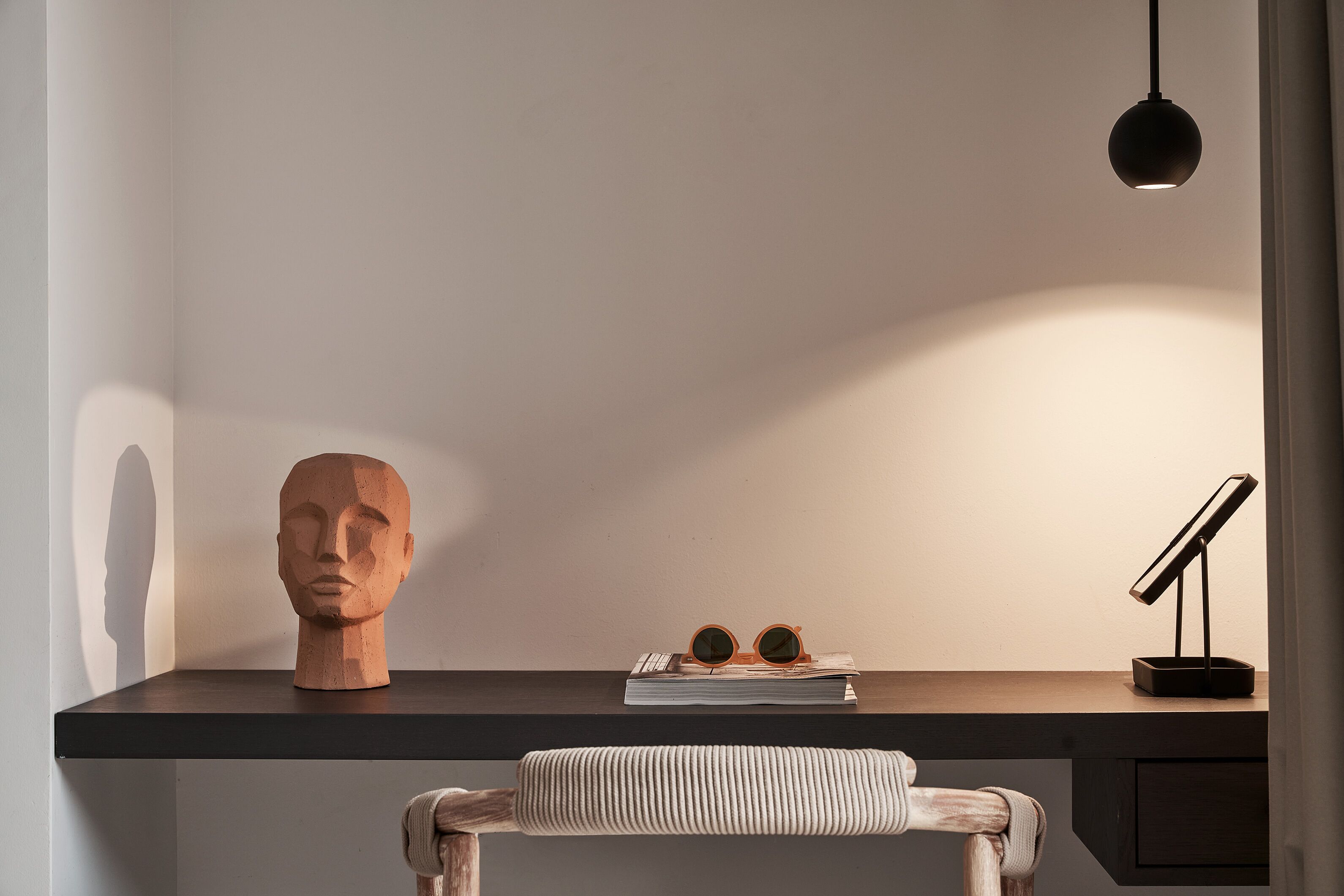 Una scrivania con una scultura di legno raffigurante una testa, un paio di occhiali e un libro.
