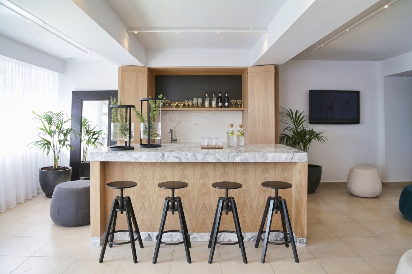 Una cocina moderna con encimera de mármol, taburetes de madera y plantas en macetas.