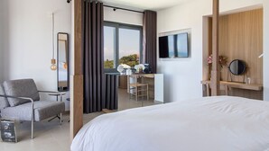 Una habitación de hotel moderna con una cama grande, un escritorio con silla, un televisor y vistas al exterior.