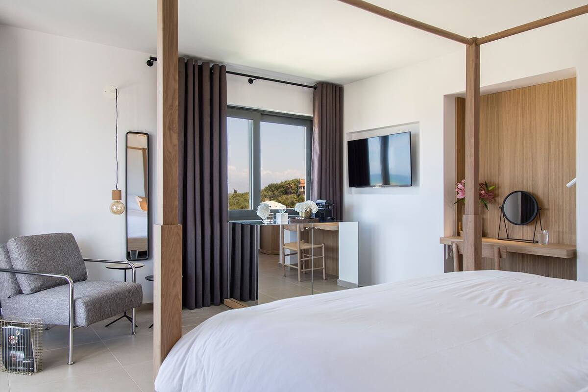Une chambre d’hôtel moderne dotée d’un grand lit, d’un bureau avec une chaise, d’une télévision et offrant une vue sur l’extérieur.