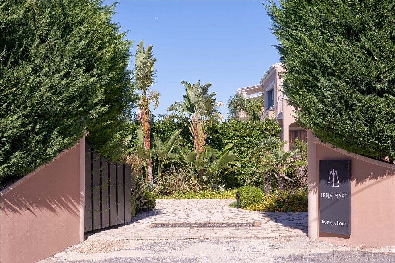 Una entrada pavimentada a un hotel, con un letrero que dice "LENA MARE Boutique Hotel".