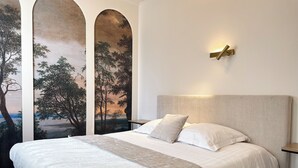 Ein Schlafzimmer mit einem großen Bett, weißer Bettwäsche, einem Kopfteil und einer Wandleuchte.