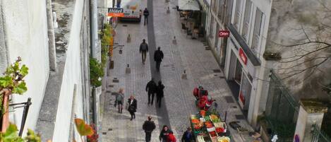 A narrow street with a market stall selling fruits and vegetables.