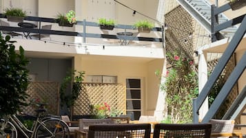 Un patio con mesas al aire libre, una bicicleta y plantas en macetas.