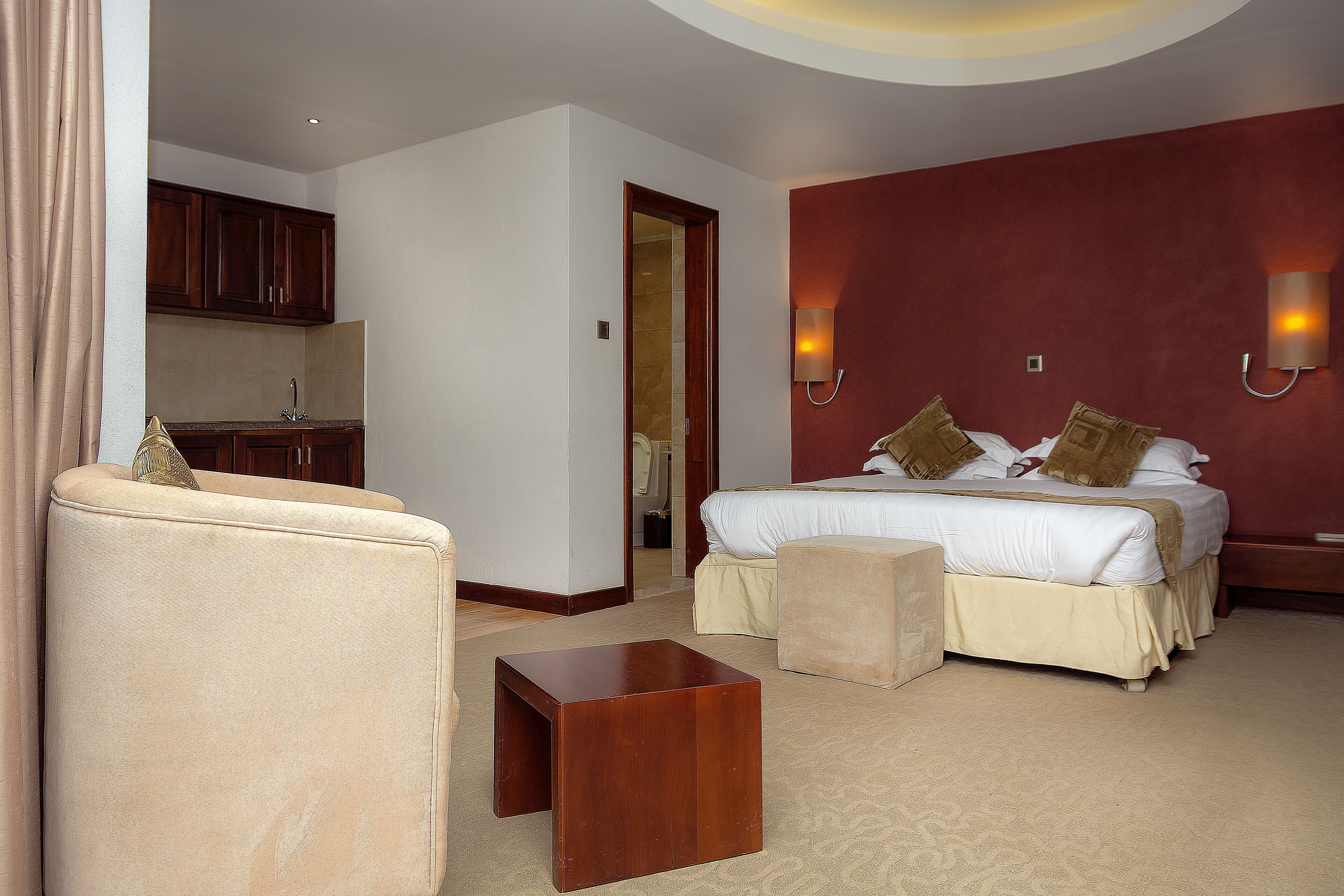 Ein Hotelzimmer mit einem Bett, einem kleinen Holztisch, einem Stuhl und einer Küchenzeile.