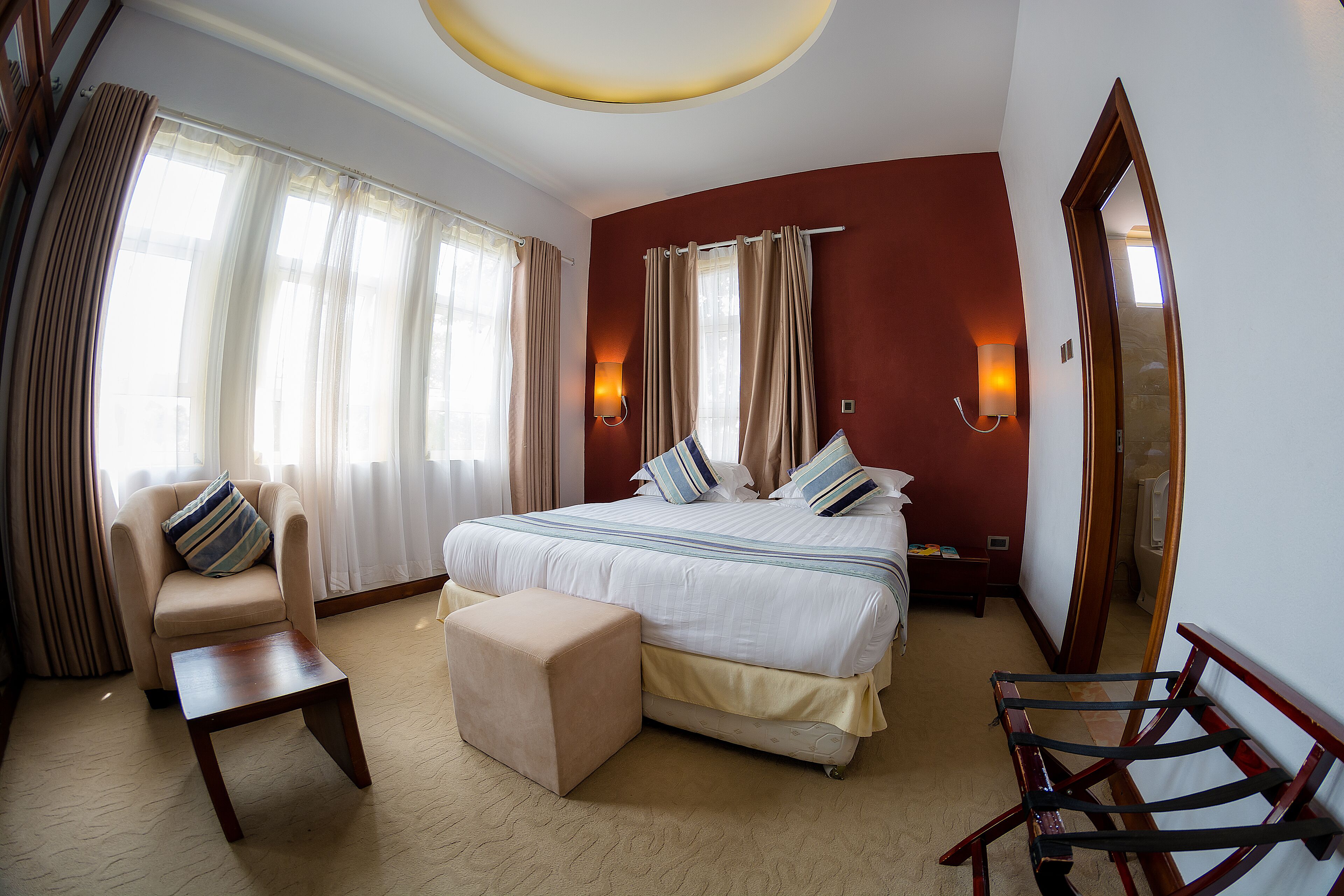 Une chambre d’hôtel avec un grand lit, une chaise, une petite table et un miroir.