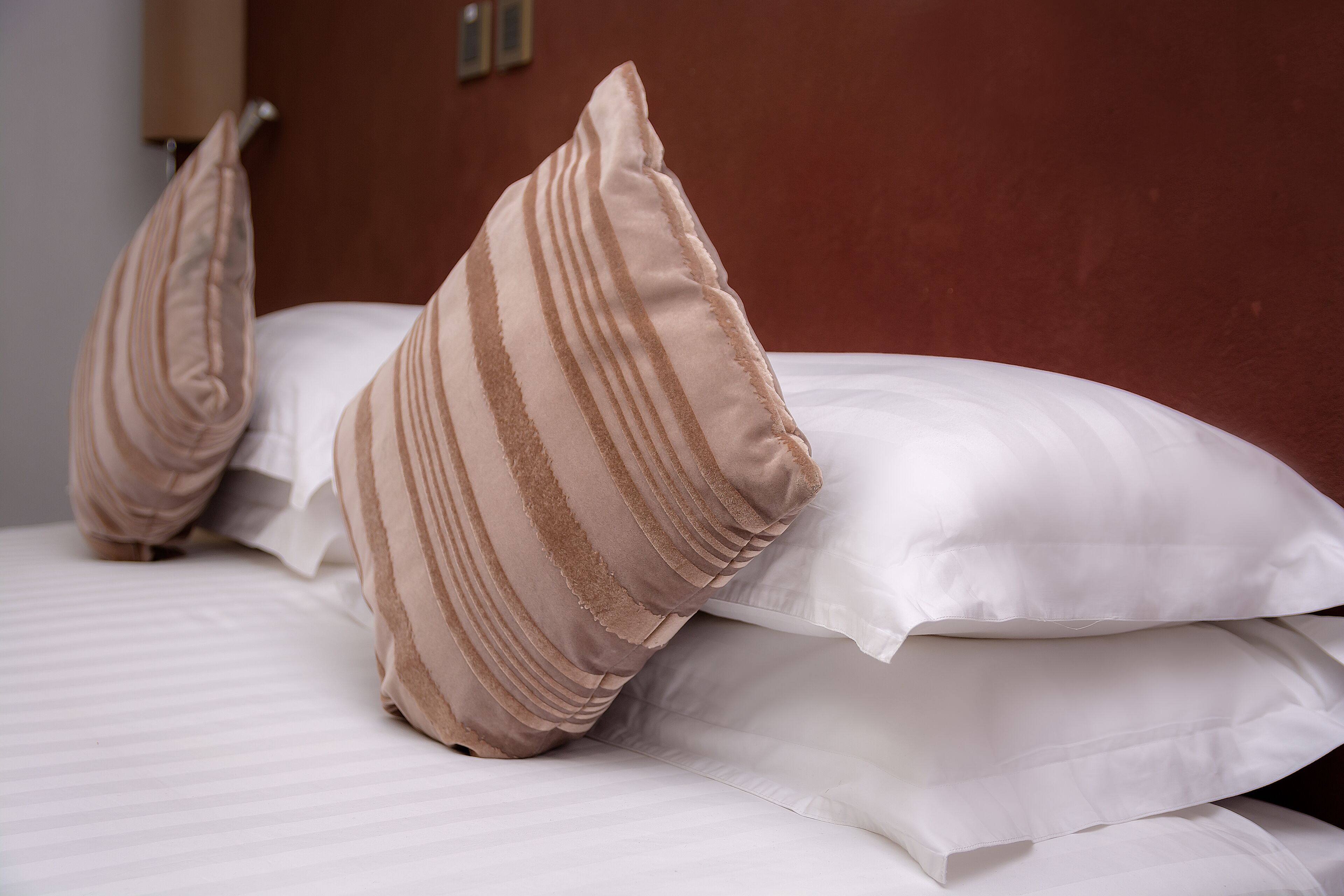A bed with white and beige striped pillows.