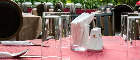 A table set for dining with a red tablecloth, clear glassware, and neatly arranged cutlery.