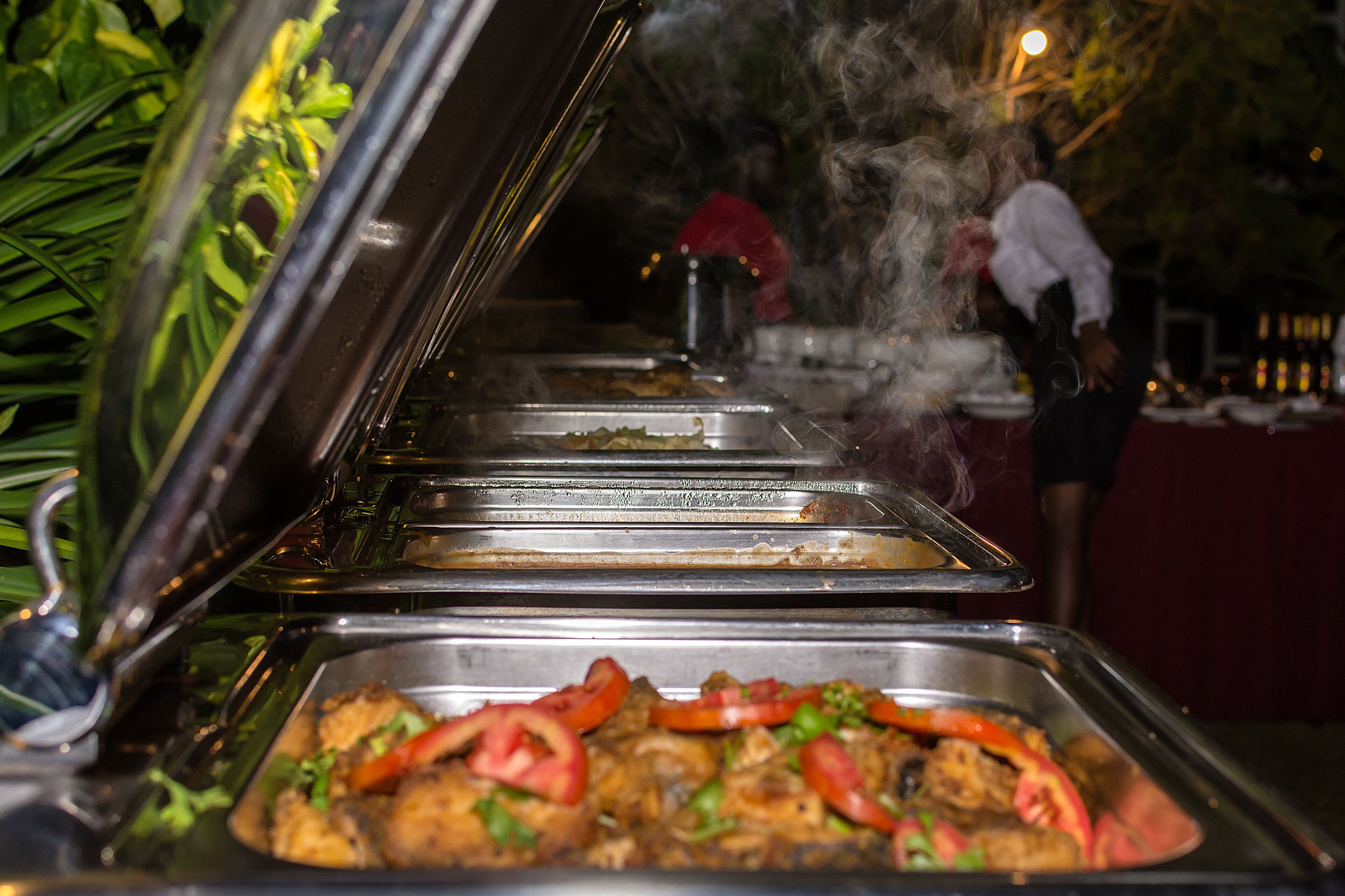 A buffet with various dishes, including a tray with food and a steam vent.