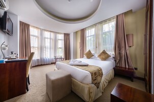 Una habitación de hotel con una cama grande, un escritorio, una silla y un televisor.