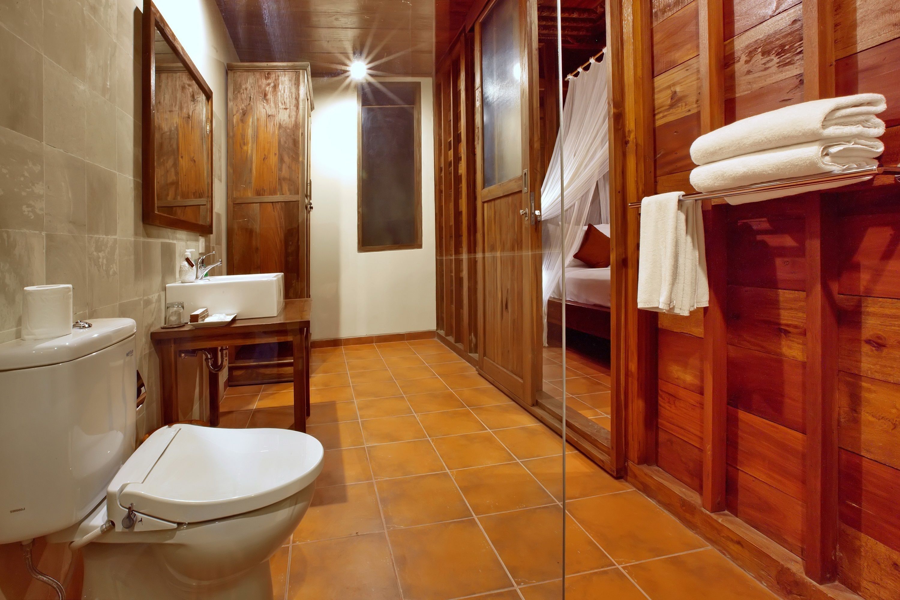 A bathroom with a toilet, sink, and wooden cabinets.