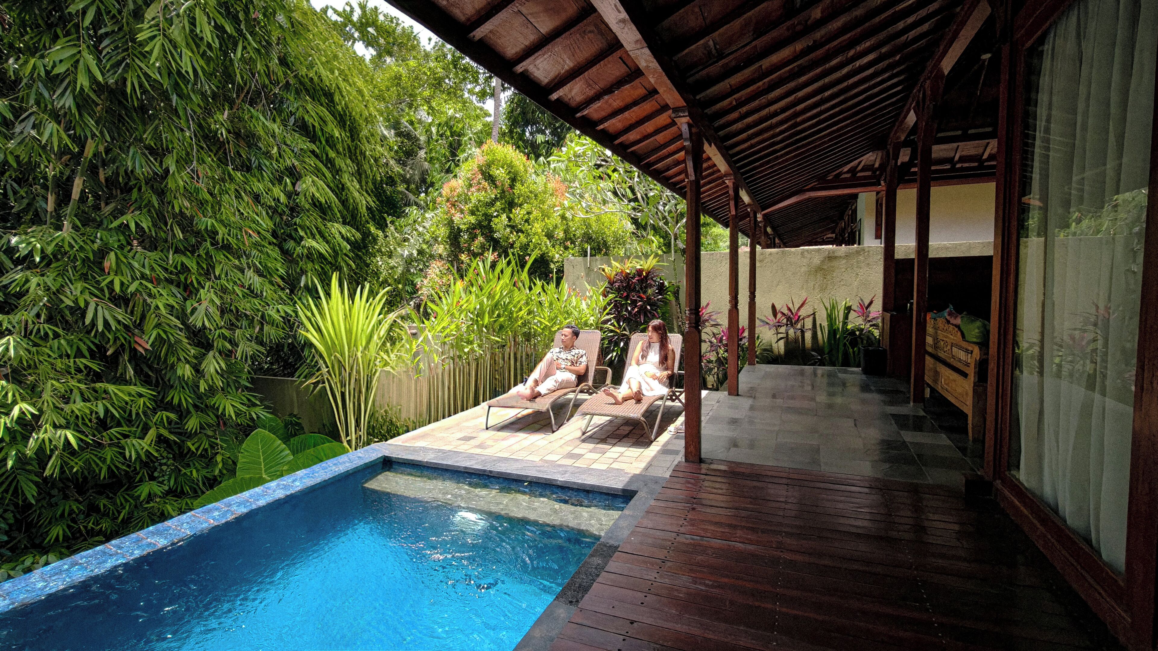 A pool area with two lounge chairs and a wooden deck.