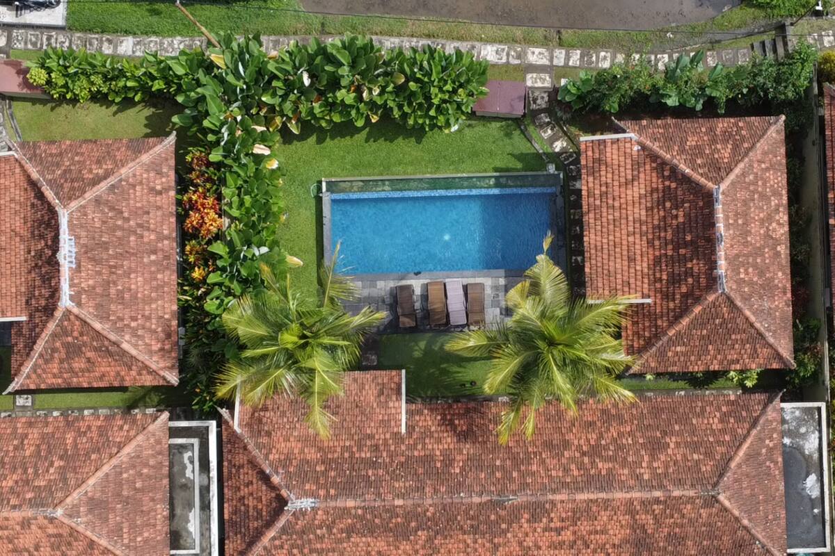 Una vista aerea di una zona residenziale con diverse case, una piscina e giardini curati.