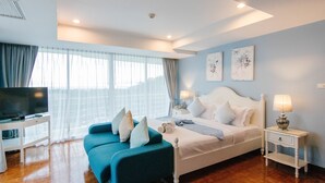 Un dormitorio con cama, televisión, sofá y mesita de noche.