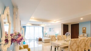 Un salón espacioso con comedor, un espejo grande y un jarrón con flores.