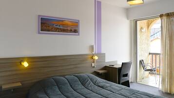 Habitación de hotel con cama, escritorio, silla, teléfono y un cuadro en la pared.