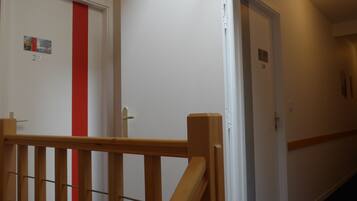 Un pasillo con puertas numeradas 22 y 24, barandas de madera y una banda roja en una de las puertas.