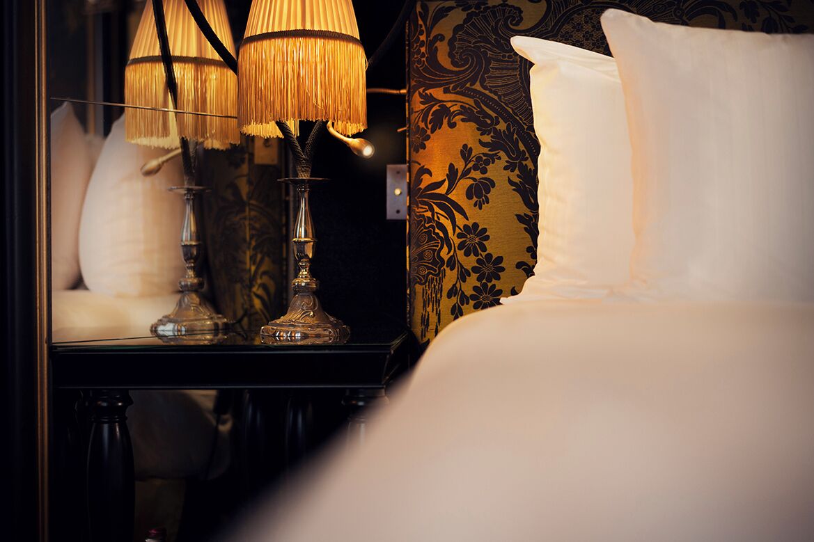 Un lit bien fait, avec du linge de lit blanc et un coussin décoratif.