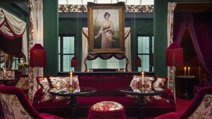 A room with two plush red velvet sofas, a central table, and a large framed portrait on the wall. - Maison Souquet, Hotel & Spa (Paris)