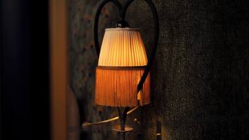 A wall-mounted lamp with a pleated shade and a black metal frame.