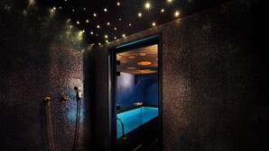 A dark, textured room with a visible shower area and a blue-tinted window. - Maison Souquet, Hotel & Spa (Paris)