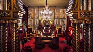 An opulent room with ornate gold and black decor, a chandelier, and a red carpet. - Maison Souquet, Hotel & Spa (Paris)
