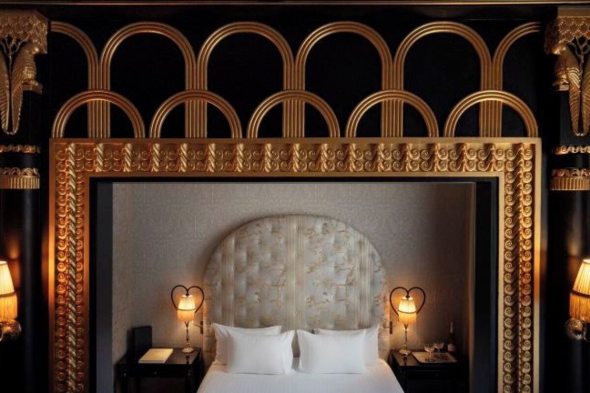 A bed with a large, ornate headboard, flanked by two nightstands with lamps.