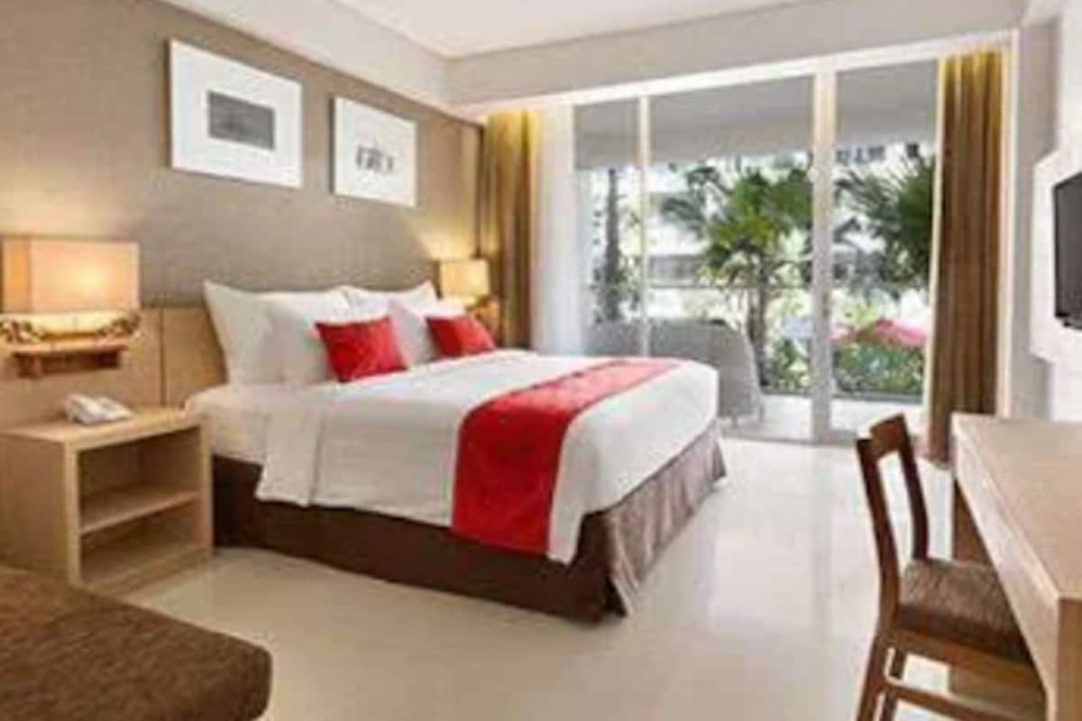 A hotel room with a bed, bedside tables, a desk, and a chair.