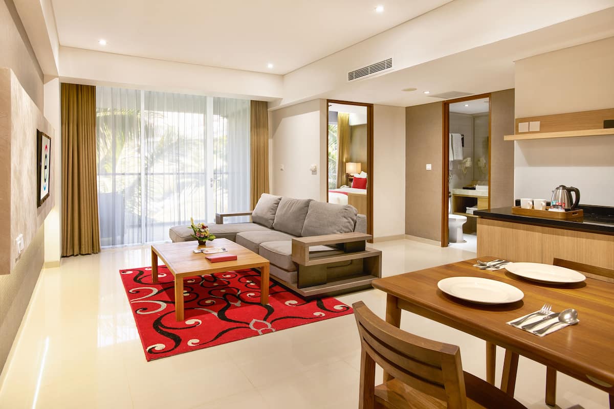 A modern hotel room with a living area, dining space, and kitchenette.