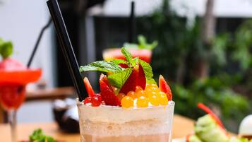 A glass of iced coffee with fruit garnish on a table with various dishes.