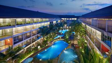 Un hotel de varios niveles con piscina central, balcones y plantas de interior.