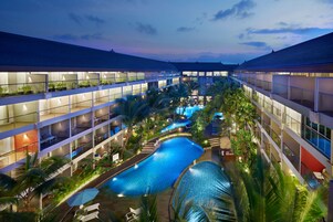 Un hotel de varios niveles con piscina central, balcones y plantas de interior.