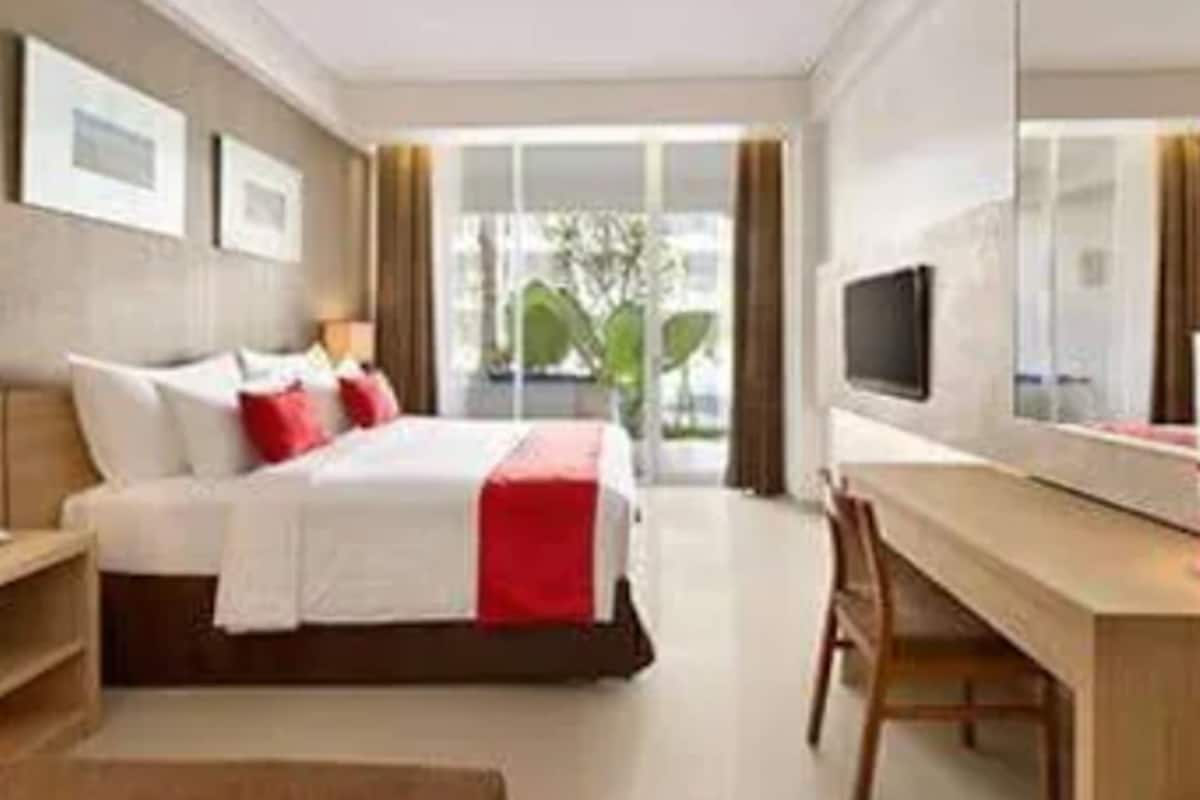 A modern hotel room with a bed, a desk, and a TV.