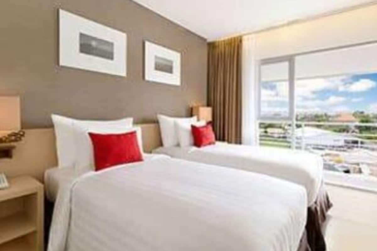 A hotel room with two beds, a large window, and a view of the outdoors.
