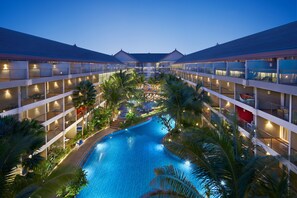 A hotel with a central swimming pool surrounded by lush greenery and multiple floors with balconies. - Ramada Encore by Wyndham Seminyak Bali (Seminyak)