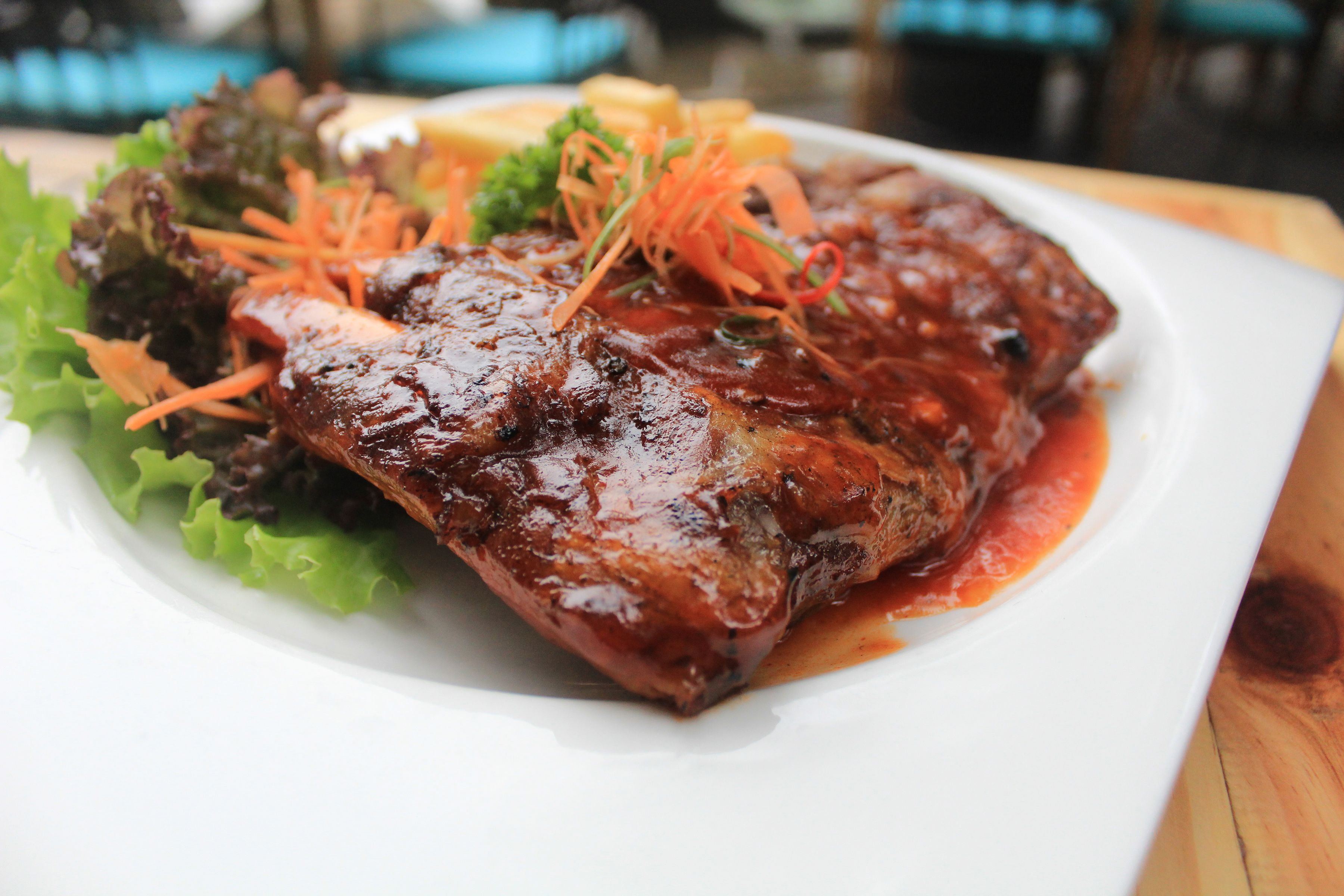 A plate of glazed meat with vegetables.