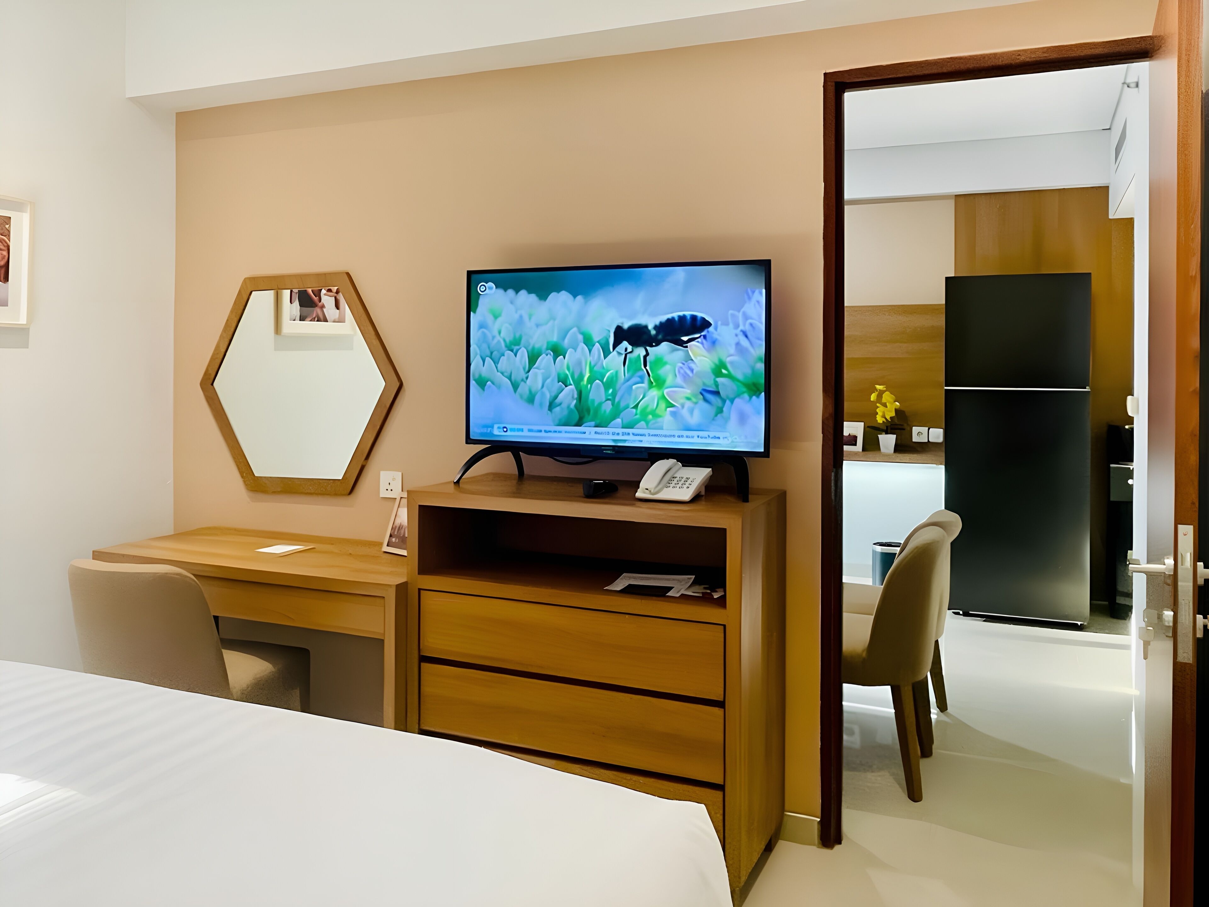 Una habitación de hotel con cama, escritorio, computadora, televisión y espejo.