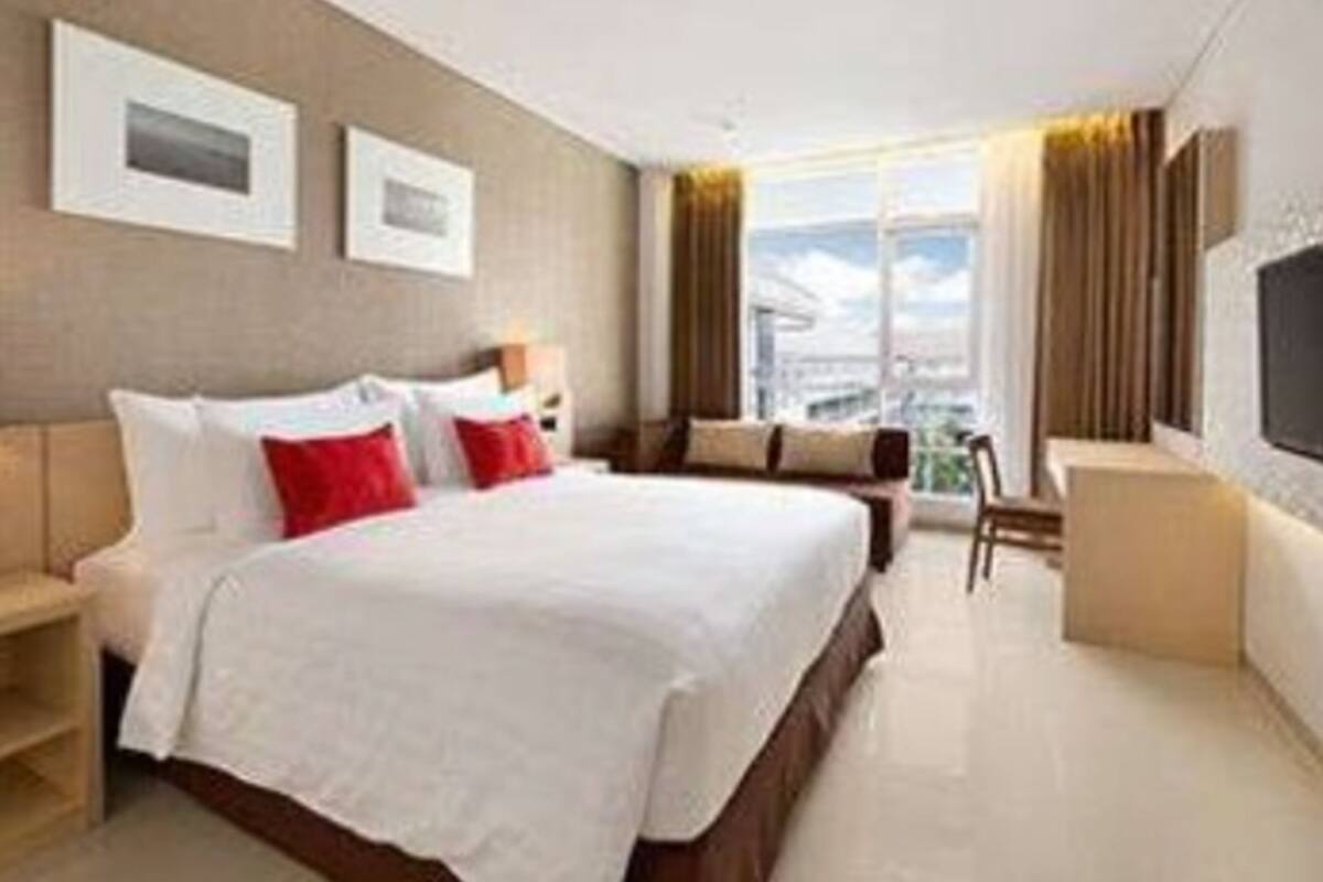 A hotel room with a large bed, a desk, and a view of the city.