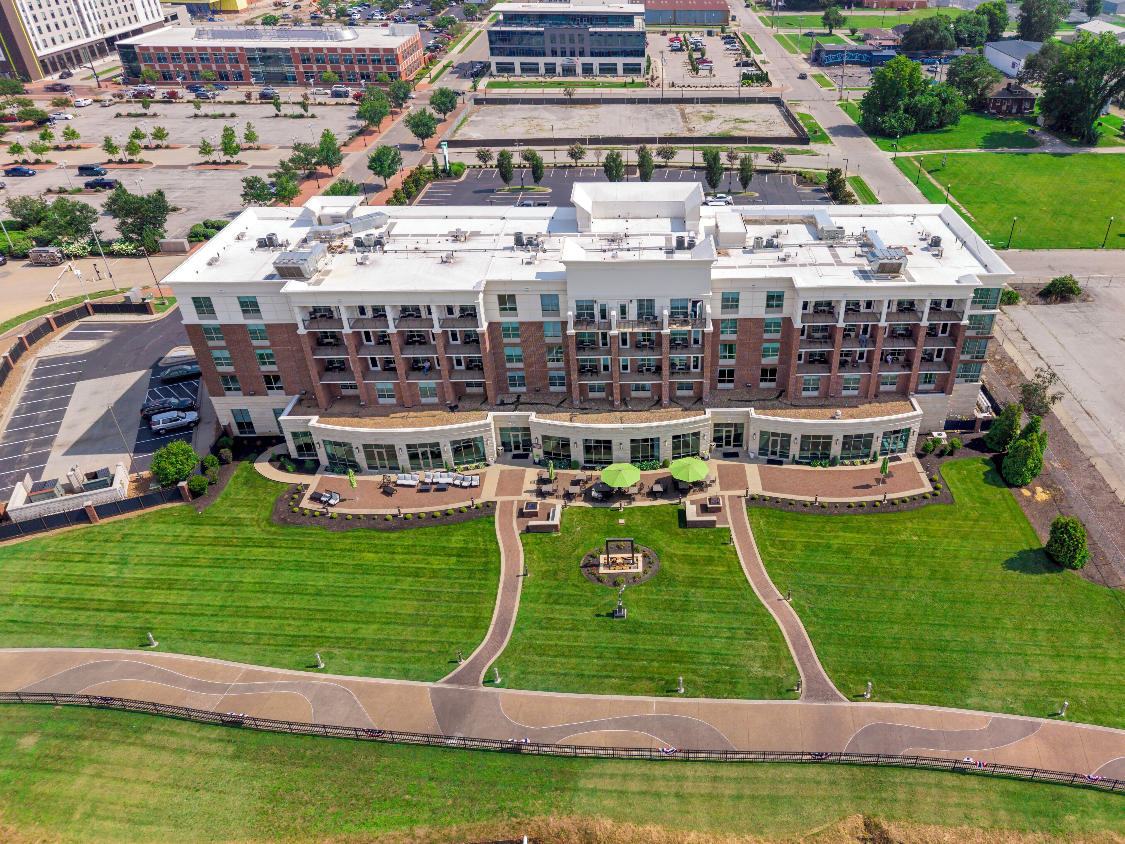 A multi-story hotel with a central courtyard, outdoor seating, and a parking lot.