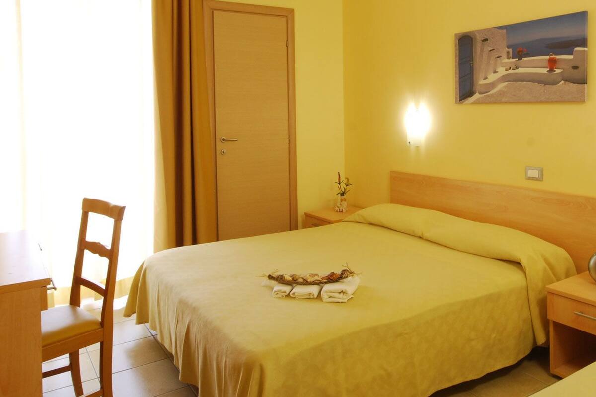 A hotel room with two beds, a desk, and a chair.