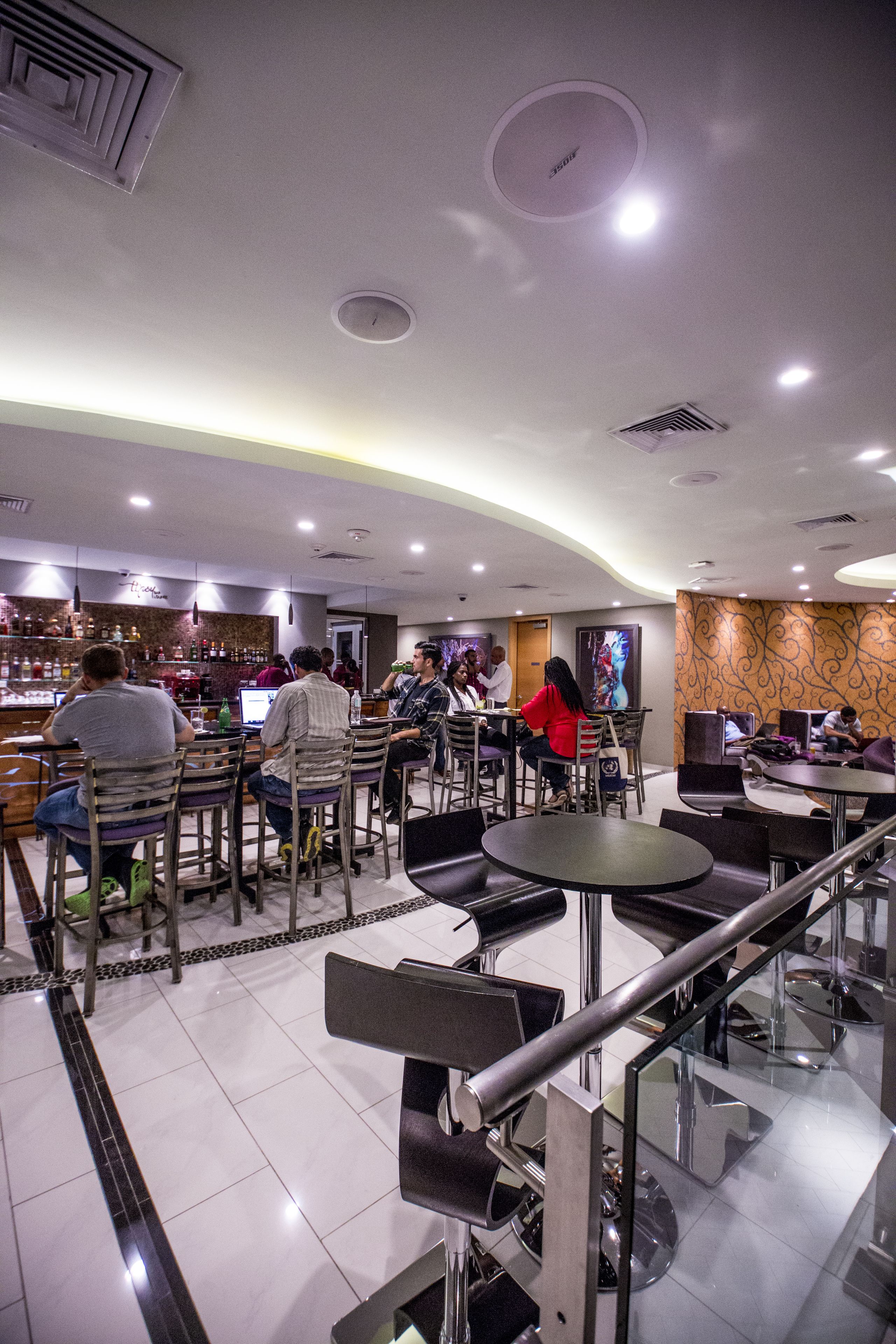 A modern restaurant with a bar area, seating arrangements, and a decorative wall.