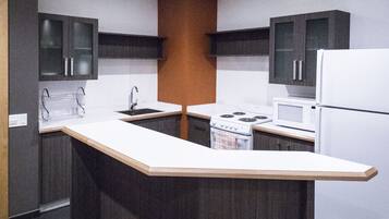 A modern kitchen with a central island, dark cabinetry, and a white countertop.