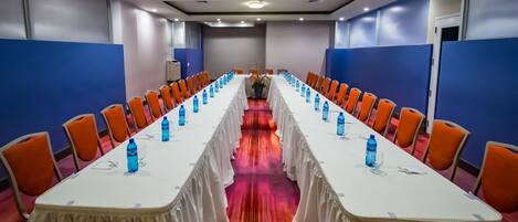 A conference room with a long table, orange chairs, and water bottles.