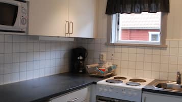 Una cocina compacta con armarios blancos, microondas, estufa y lavamanos.
