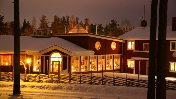A snow-covered building with a large entrance and a visible restaurant or cafe area. - Hotell Moskogen (Leksand)