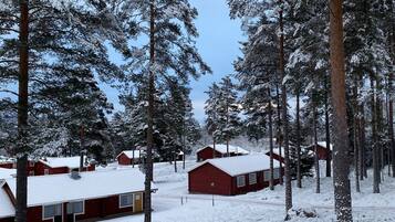 Bosque nevado con cabañas rojas y cielo despejado.