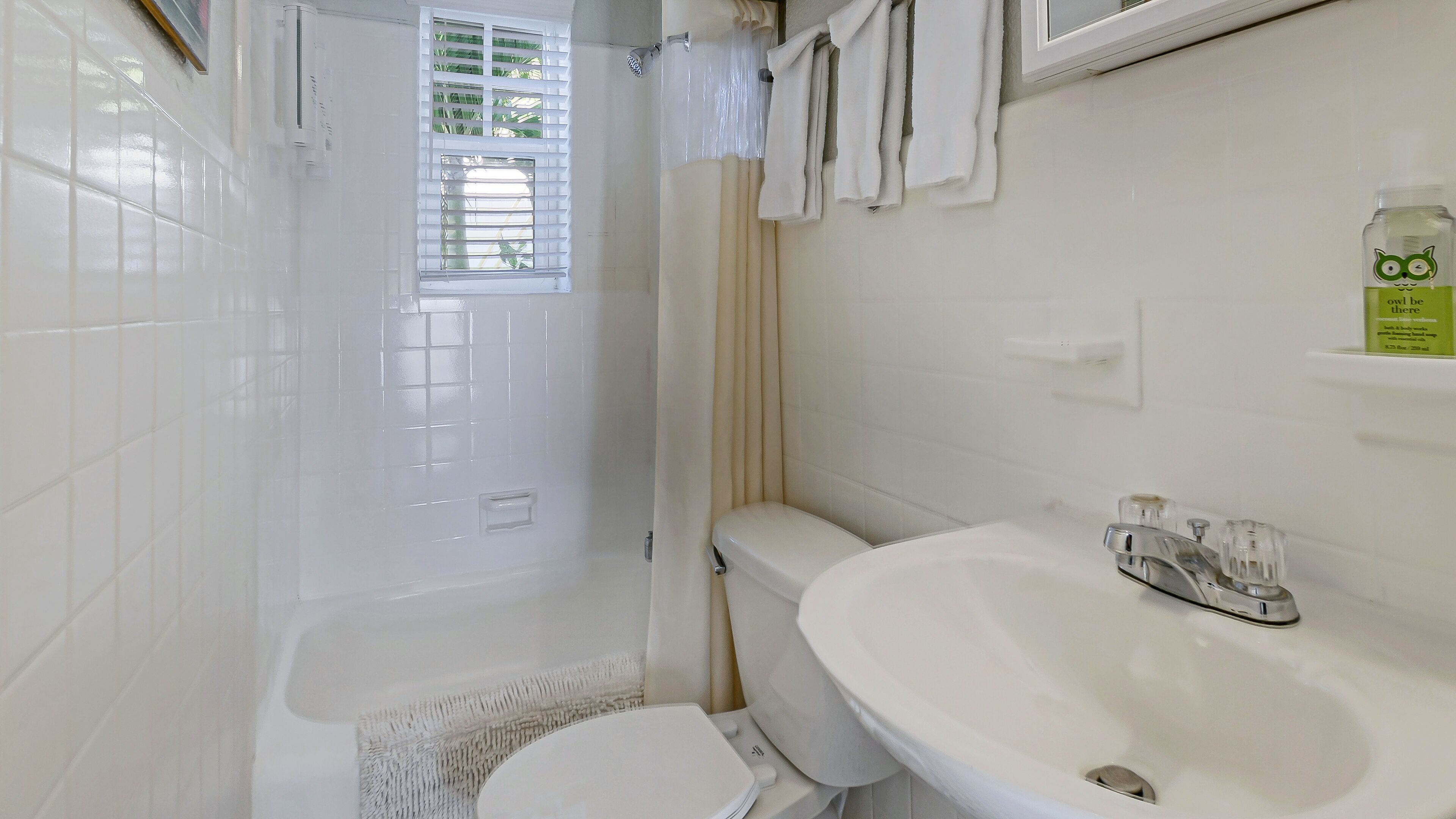 A bathroom with a white toilet, a sink, and a shower area.