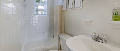 A bathroom with a white toilet, a sink, and a shower area.